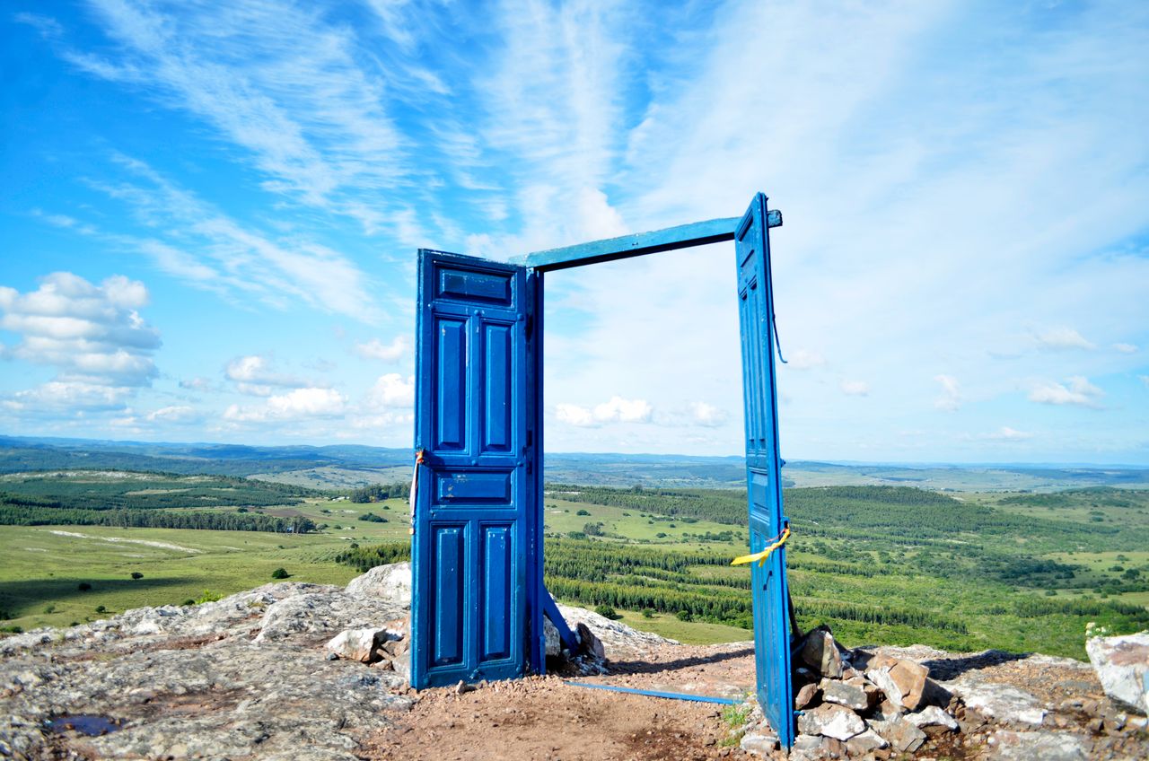 our-services-1 A vibrant blue door frames a scenic landscape in Departamento de Maldonado, Uruguay.