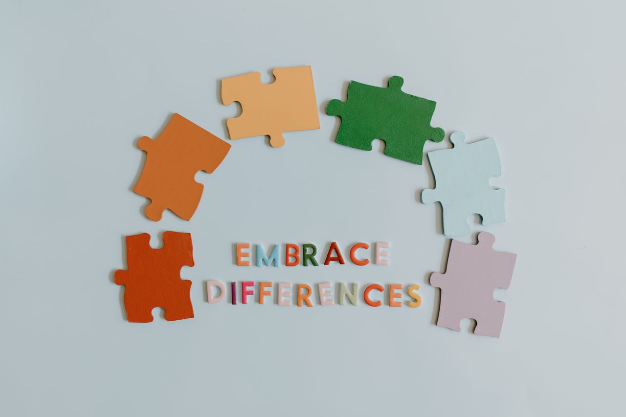 Colorful puzzle pieces and slogan embracing diversity on a white background.